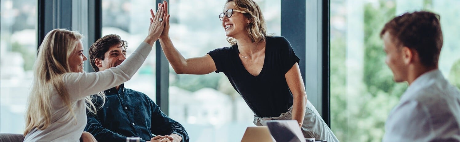 Two women highfiving at a boardroom table