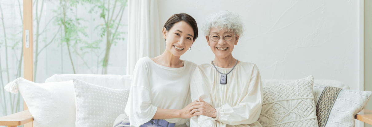 Woman with grandmother smiling sittingin cozy neutral living room.