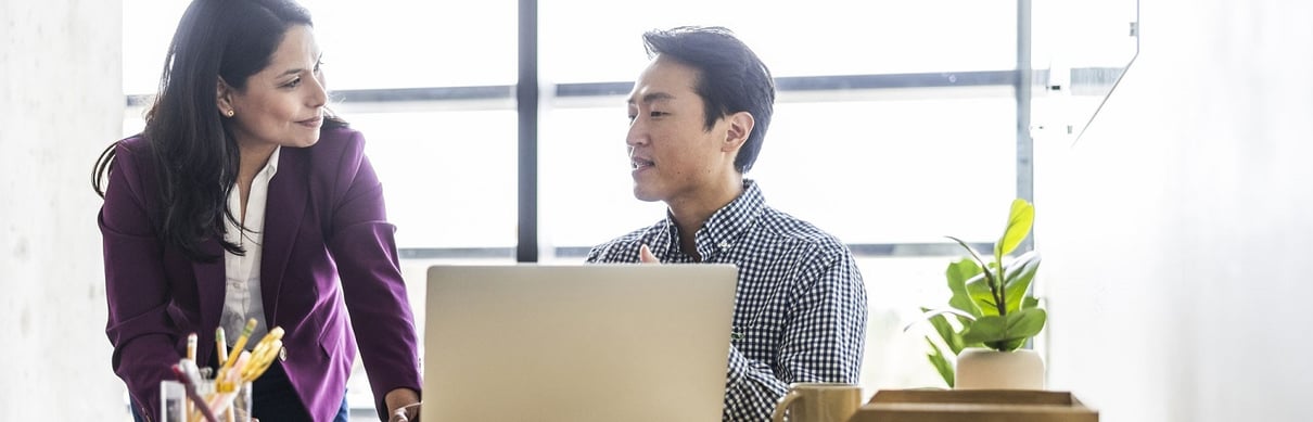 Man sitting at desk speaking to woman