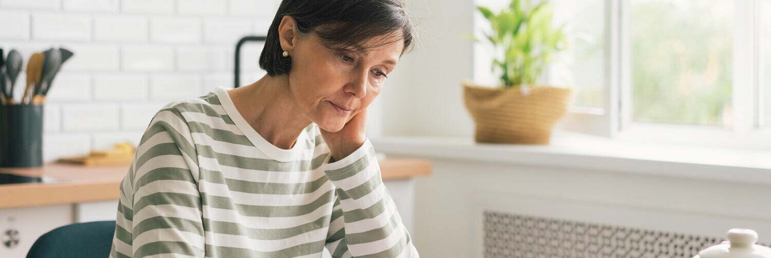 Woman sitting at kitchen table looking down