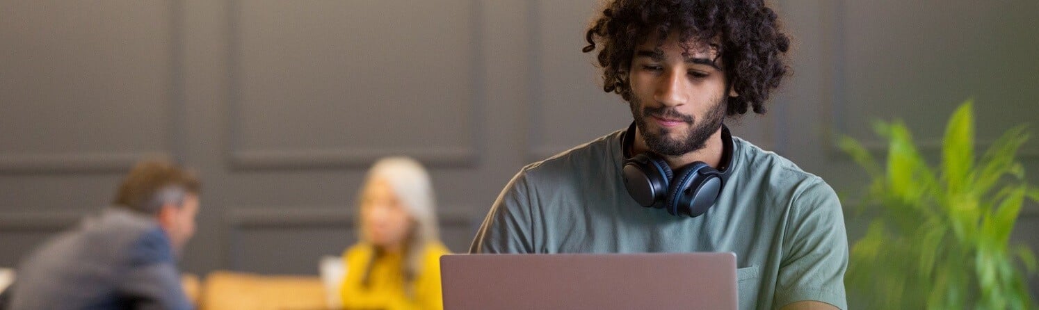 Man-sitting-at-desk-with-laptop-and-headphones