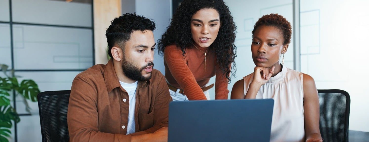 Three people in an office looking at a laptop