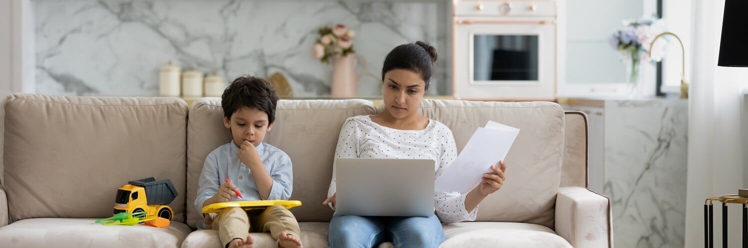 Femme-assise-sur-un-couchage-avec-un-ordinateur-portable-à-côté-de-son-fils