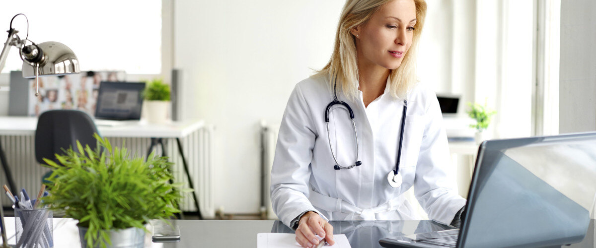 A female doctor working on medical expertise while sitting at desk in front of laptop.