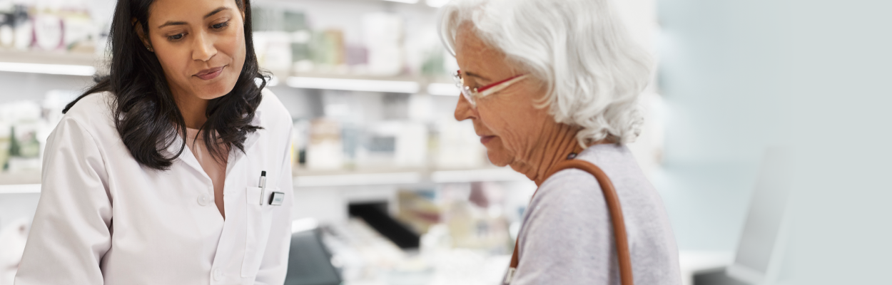 Female pharmacist with older female patient in pharmacy setting