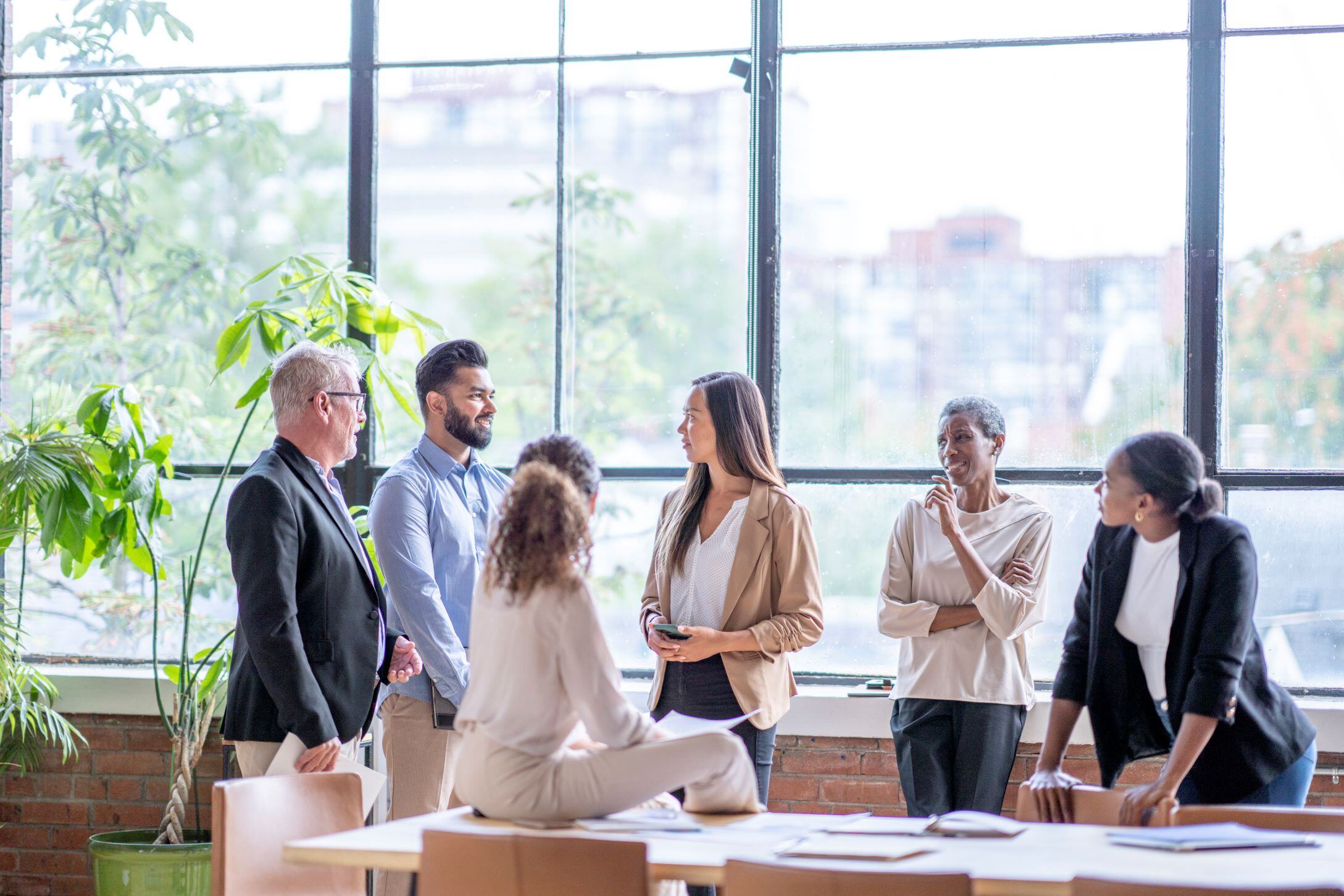 Group of employees standing talking around a boardroom table