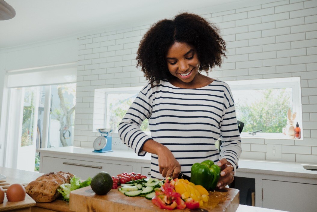 Une femme hache des légumes dans une cuisine.