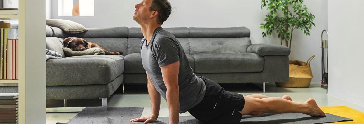 Man in his living room attending virtual yoga class practicing yoga poses to improve his sleep quality