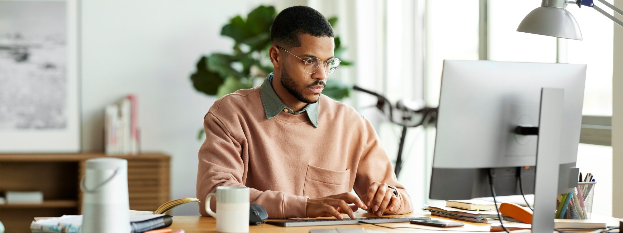 Un homme heureux et en bonne santé, assis dans son espace de travail à domicile confortable avec son ordinateur portable.