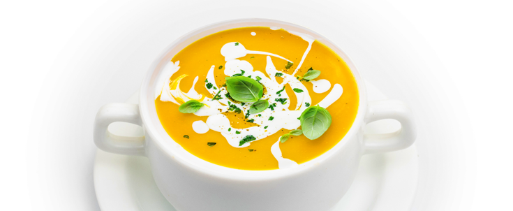 Potage doré au curcuma avec des feuilles de basilic sur le dessus