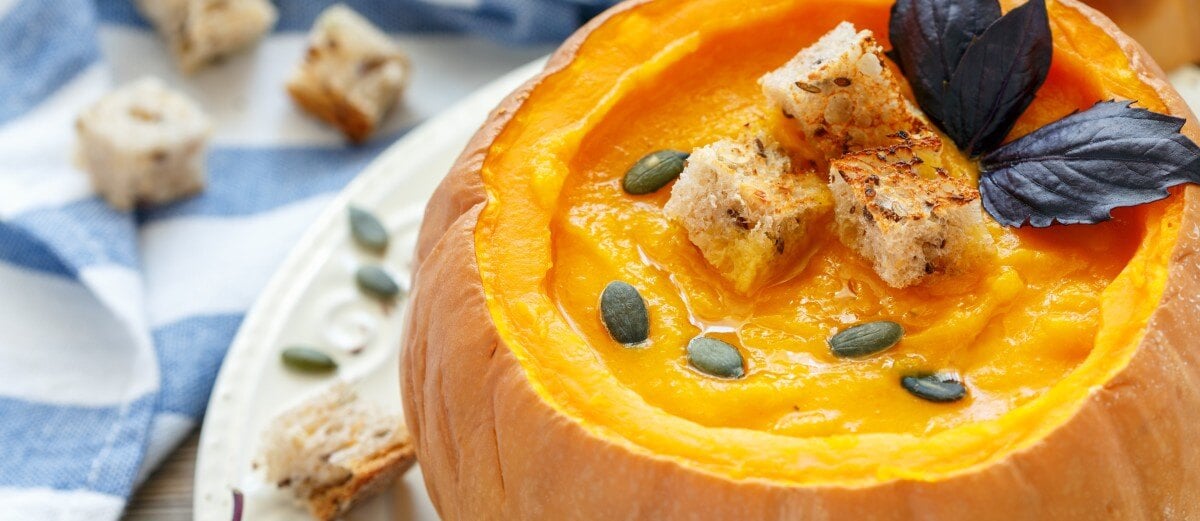 soup in a pumpkin with bread and seeds on top