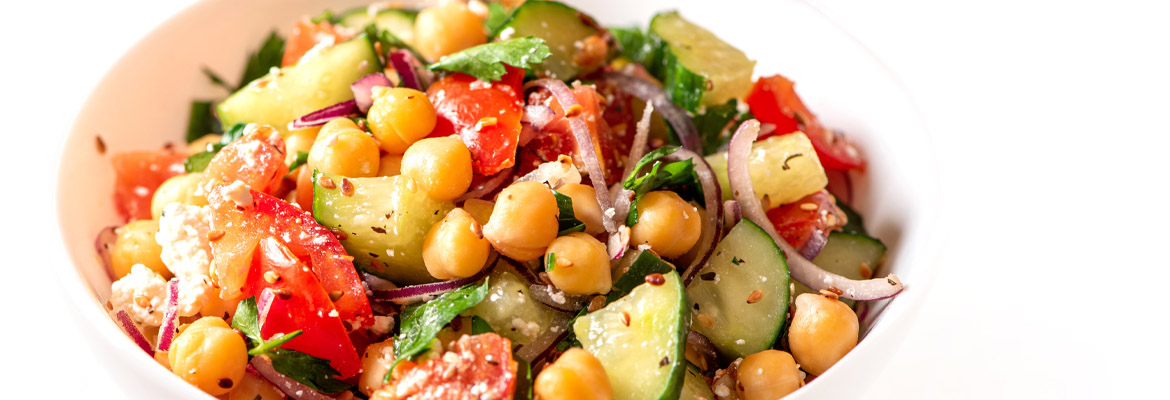 Une salade composée de pois chiches, de tomates, de concombres et d'oignons.