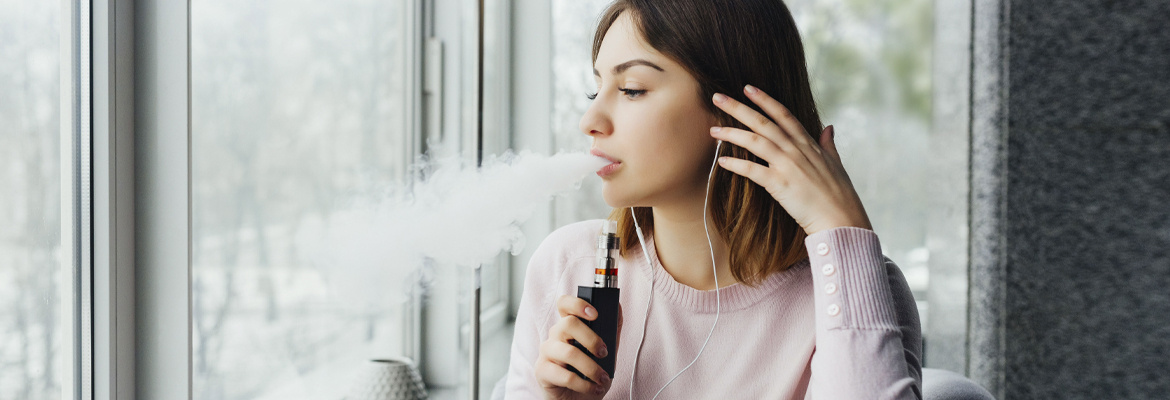 A young woman exhaling from a vape pen