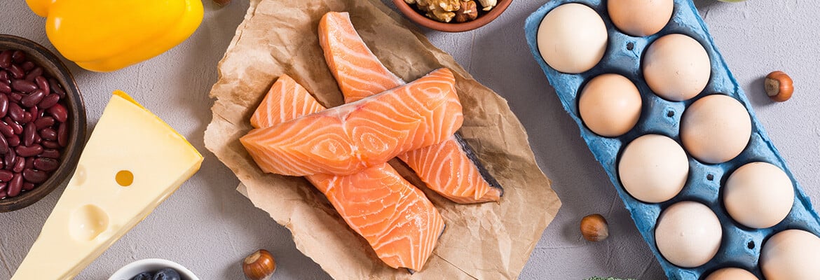 A number of ketogenic foods on a table: Beans, cheese, salmon, and egs