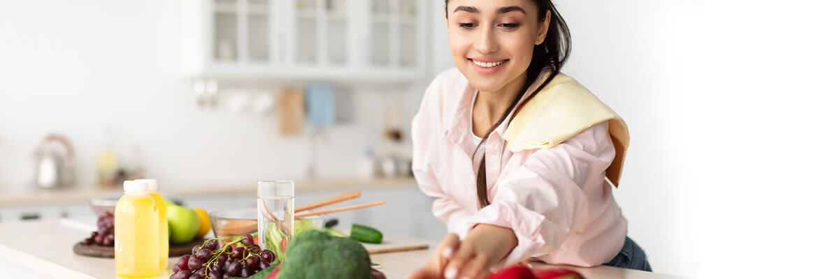 Une jeune femme préparant une salade dans sa cuisine.