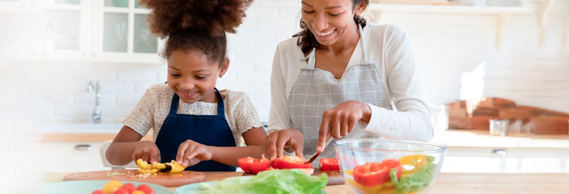 Une mère et sa fille coupent des légumes pour une salade.