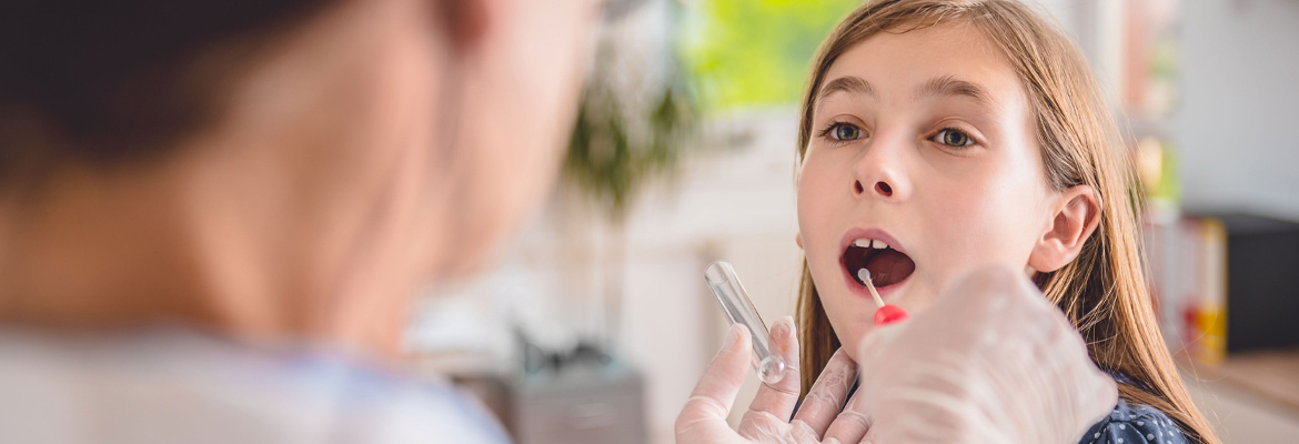 Un médecin fait un prélèvement buccal sur une jeune fille.