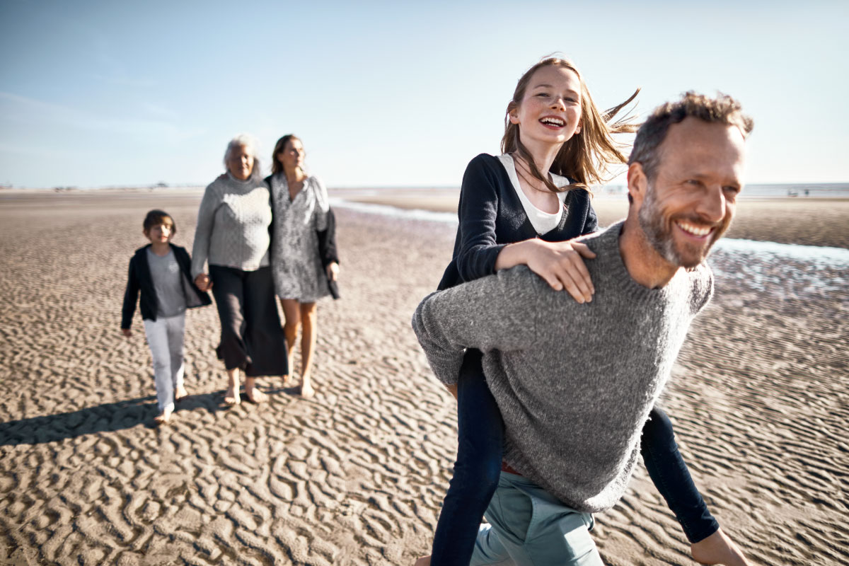 family walking on beach with elderly person