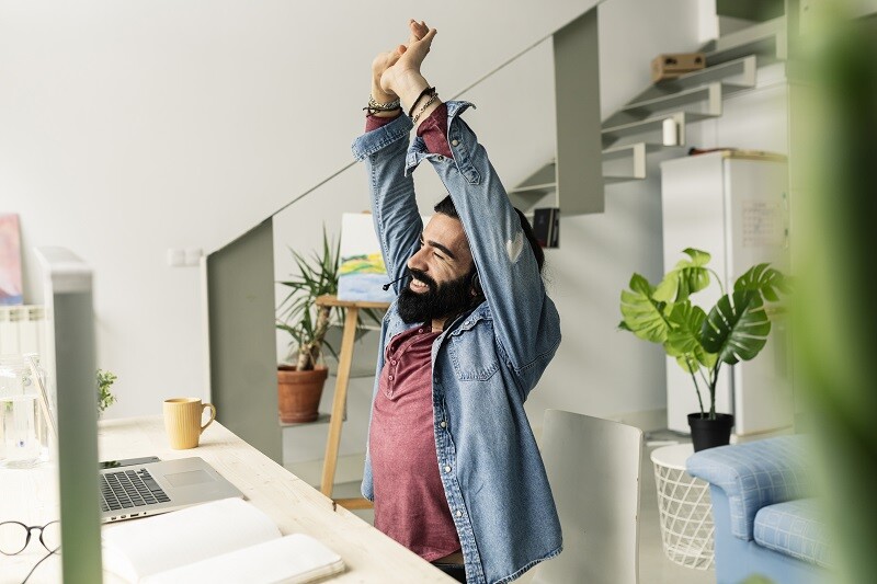 man sitting at his desk stretching 