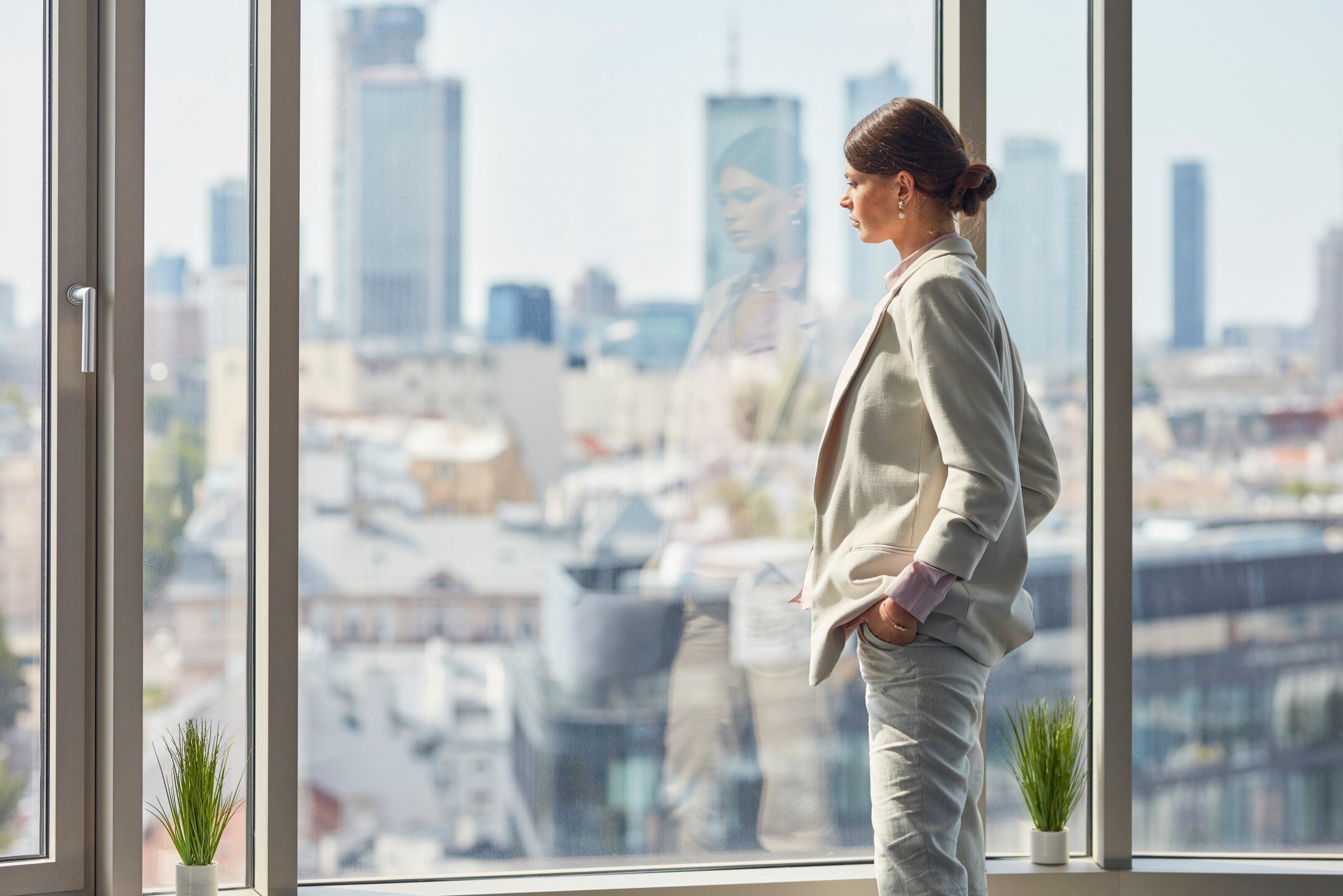 woman in an office standing looking outside window