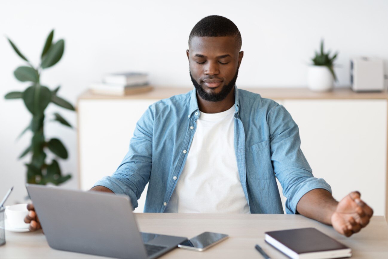 A man meditating at his desk to recover from burnout