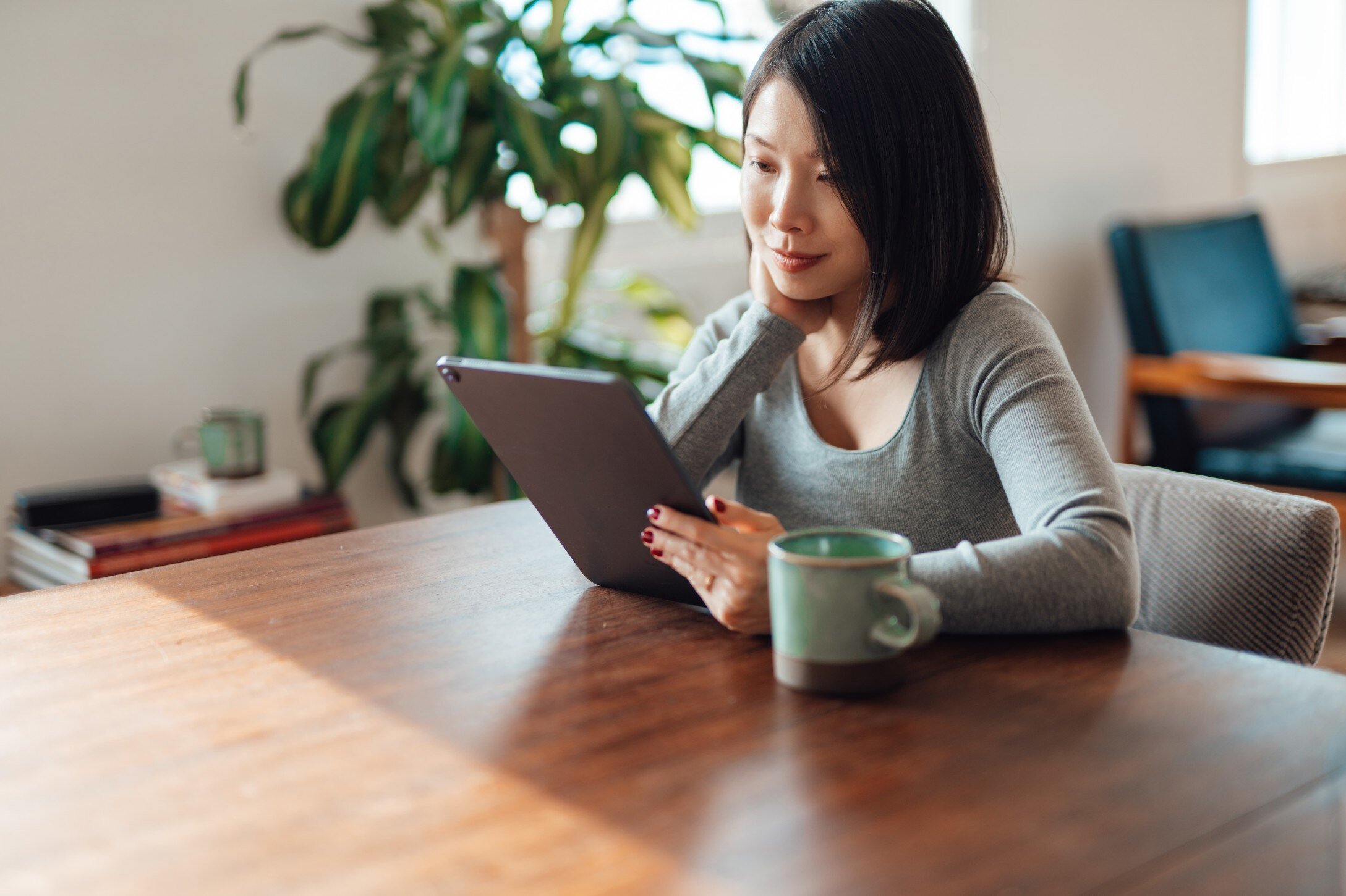 Woman sitting at a table looking at a tablet