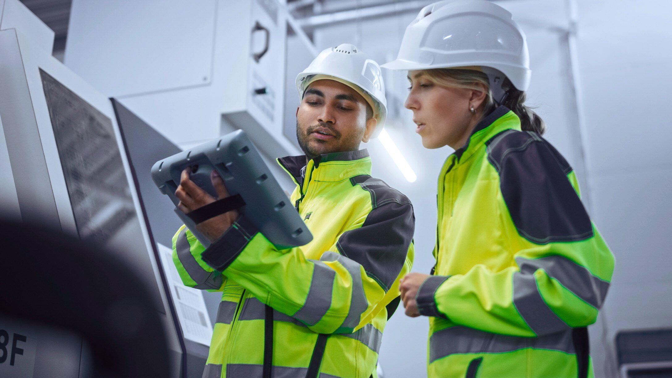 Man and woman in hardhats looking at tablet