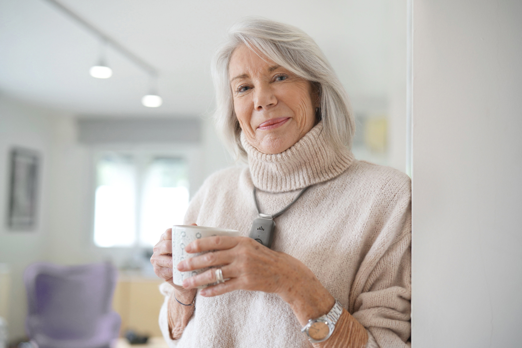 Avoiding winter slips, falls, and injuries. Woman wearing a medical alert pendant and drinking something warm