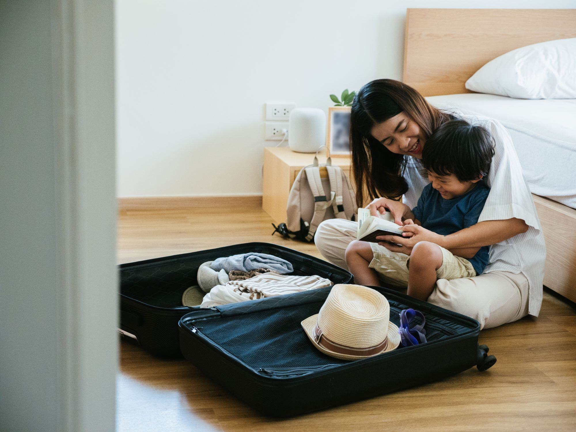 Mère et enfant heureux assis devant une valise en train de faire leurs bagages  