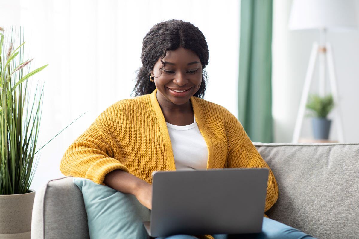 Femme assise sur un canapé avec un ordinateur portable