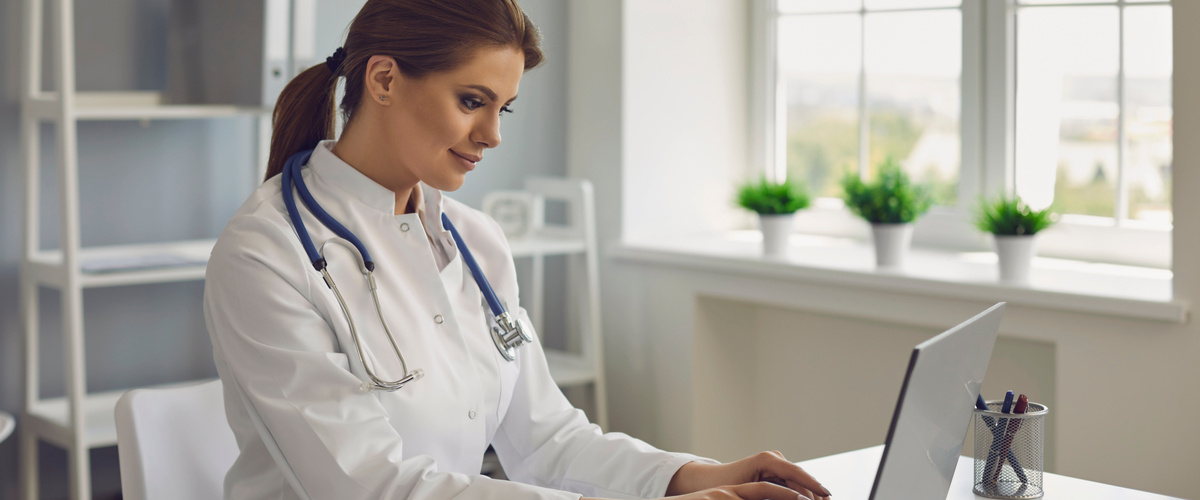 A female physician working on her laptop.